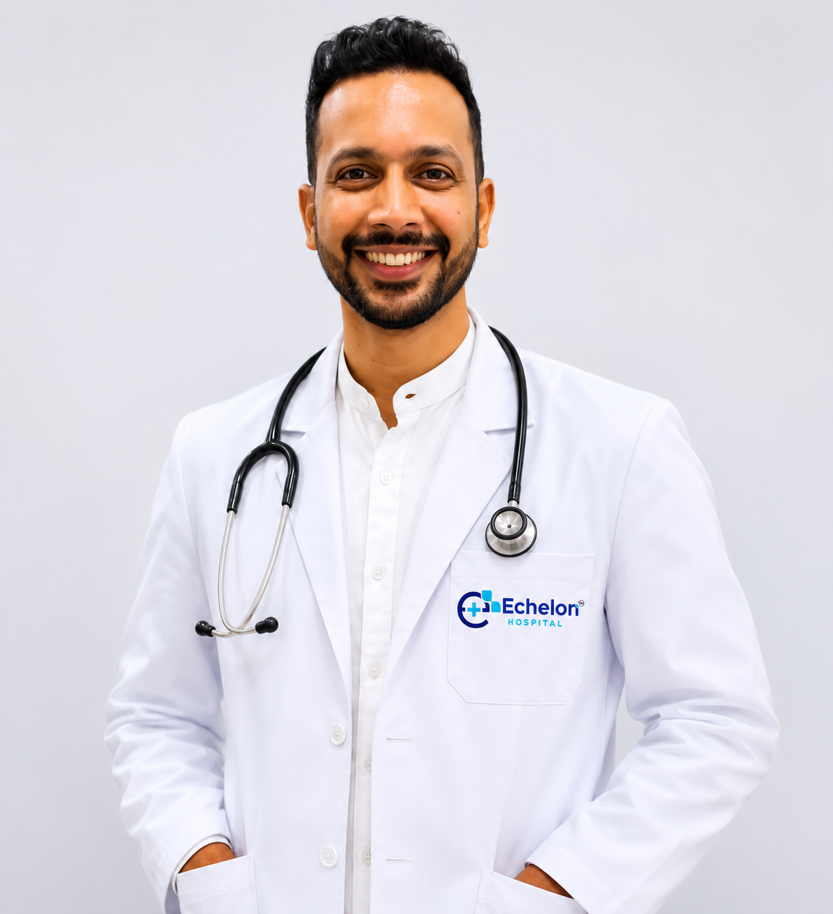 Male doctor in a white coat with stethoscope, smiling, branded with Echelon Hospital logo on the pocket.