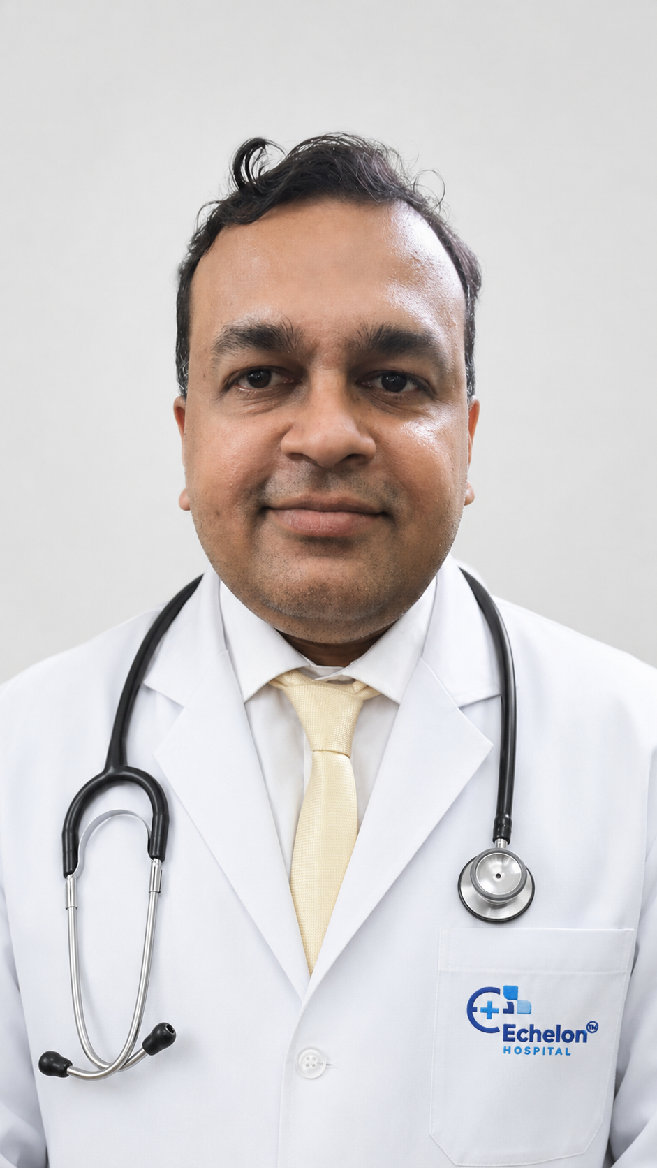 Male doctor in a white coat with a stethoscope around his neck, standing against a neutral background; pocket shows the Echelon Hospital logo.
