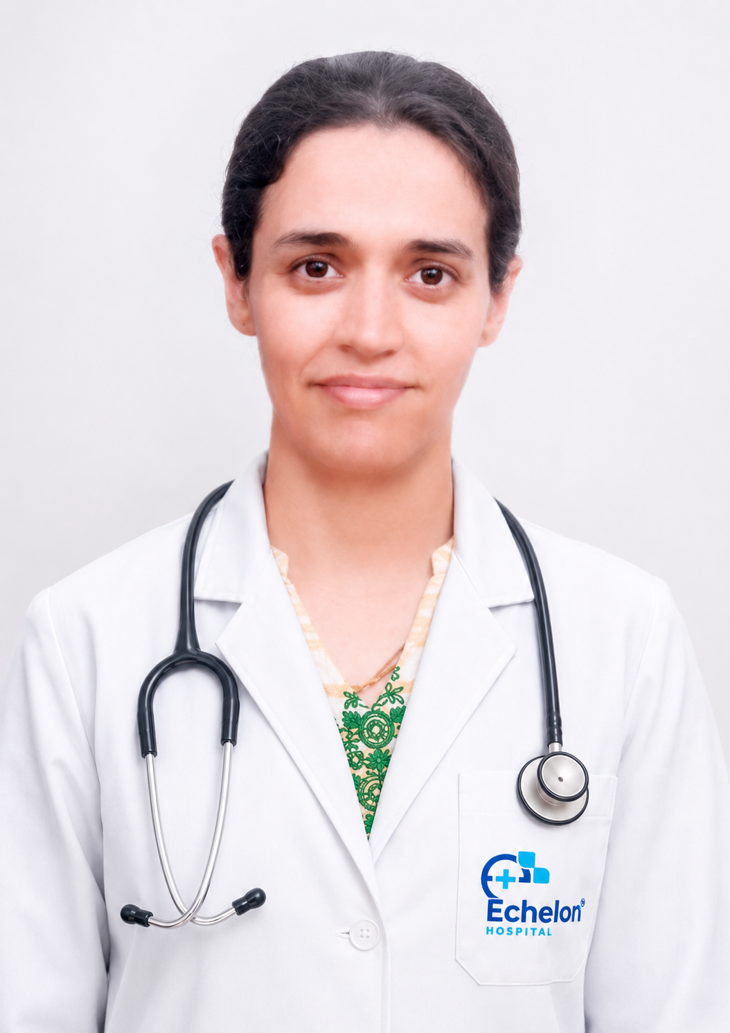 Portrait of a female doctor in a white coat with a stethoscope around her neck, standing against a light background; Echelon Hospital logo visible on her pocket.