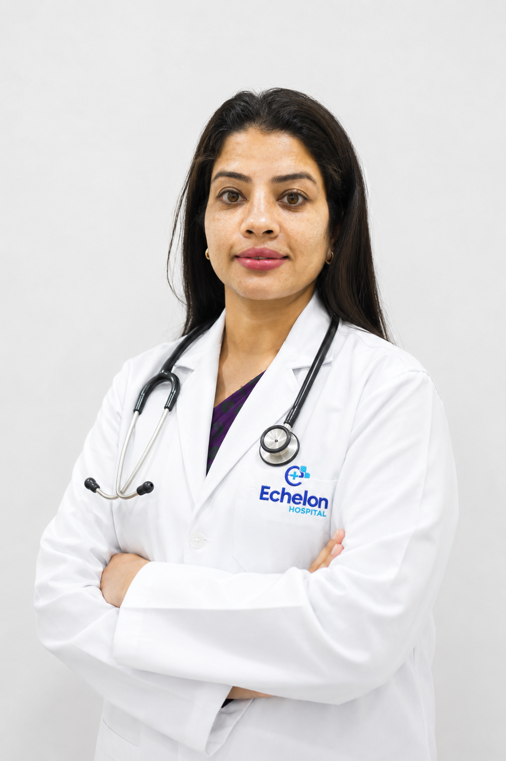 Female doctor with a stethoscope around her neck, wearing a white coat with the Echelon Hospital logo, arms crossed.