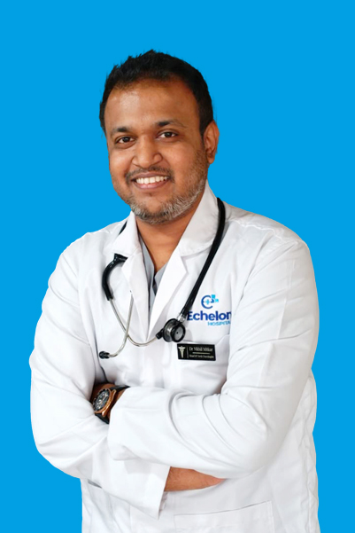 Male doctor in a white coat with a stethoscope, arms crossed, smiling against a blue background.