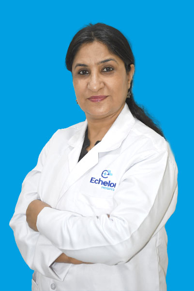 Portrait of a female doctor in a white coat with arms crossed against a blue background, Echelon Hospital logo on the coat.
