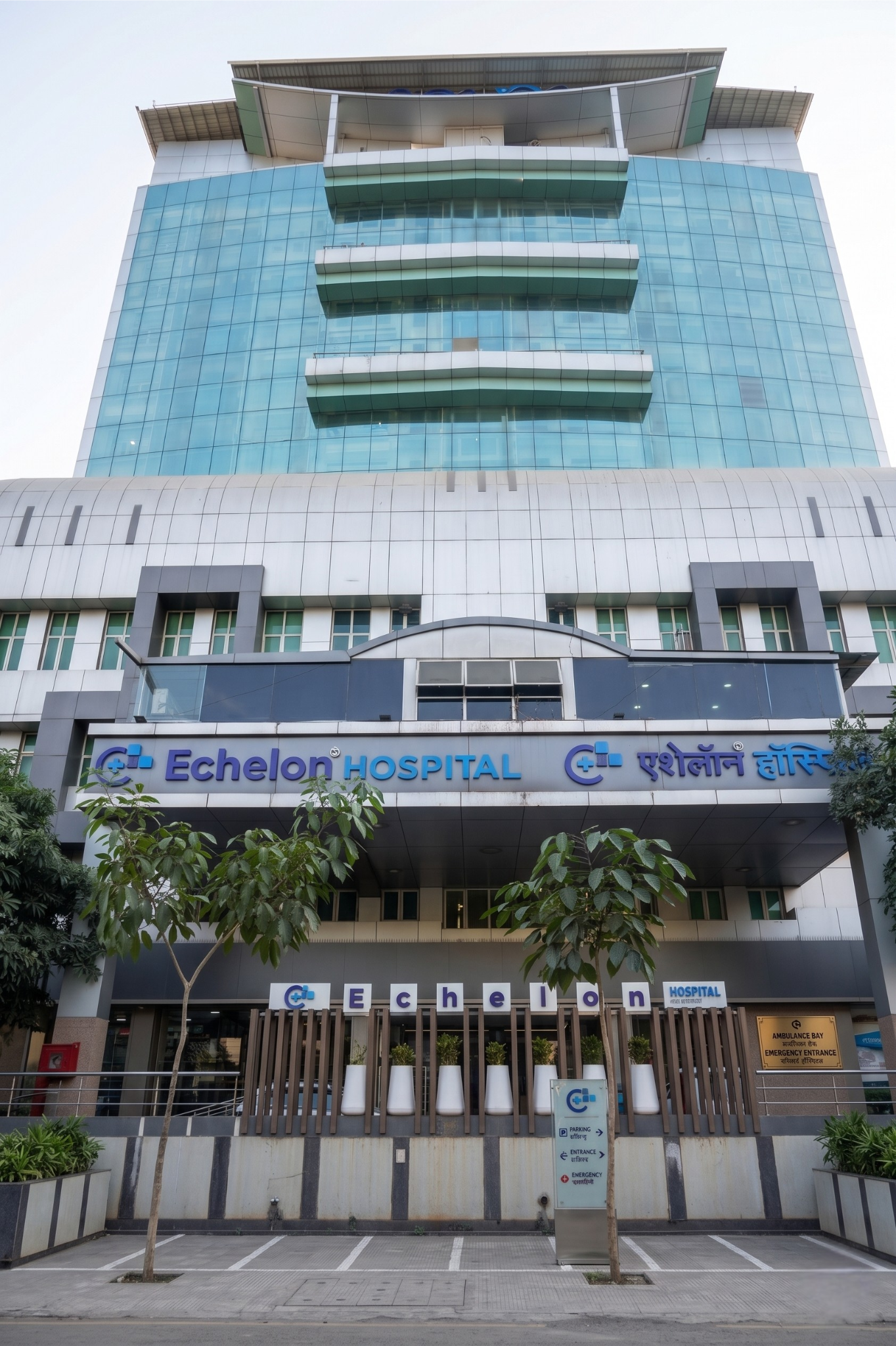 Front view of Echelon Hospital—a tall glass-clad building with blue windows and the hospital sign at the entrance.