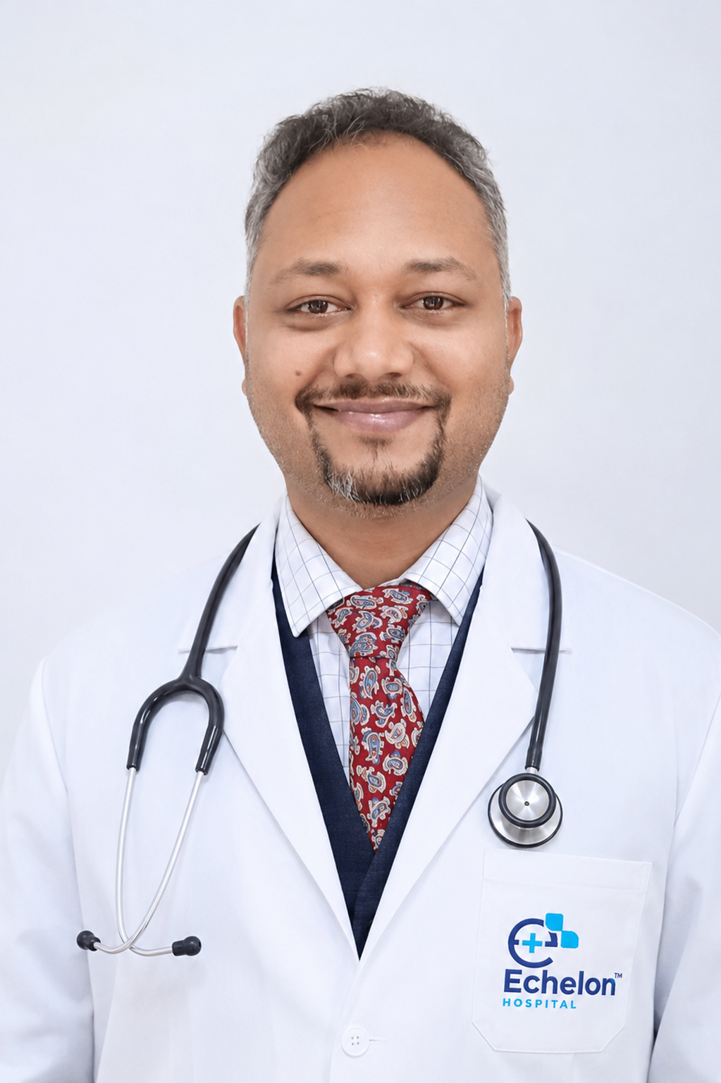 Smiling male doctor in a white coat with a stethoscope, pocket badge showing Echelon Hospital logo.