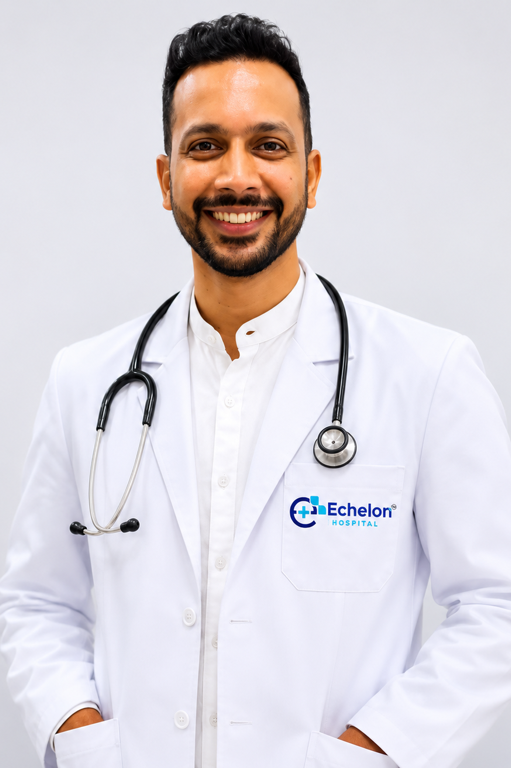 Smiling male doctor in a white coat with stethoscope, Echelon Hospital logo on the pocket.