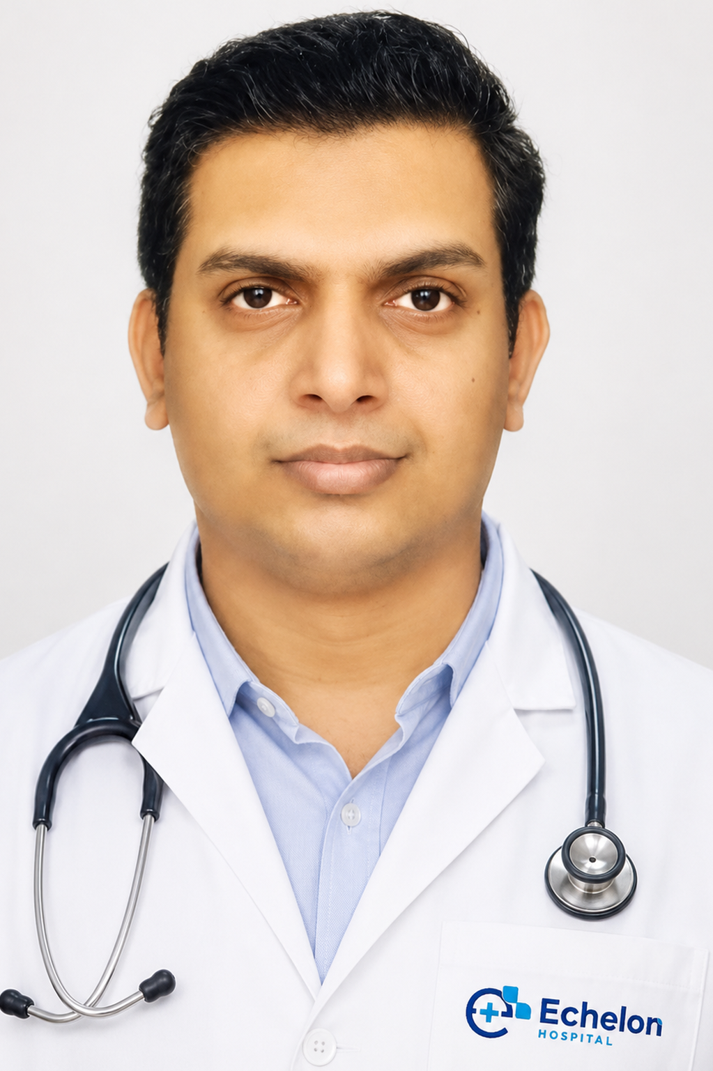 Portrait of a doctor in a white coat with a stethoscope, wearing a light blue shirt and Echelon Hospital logo visible on the pocket area.