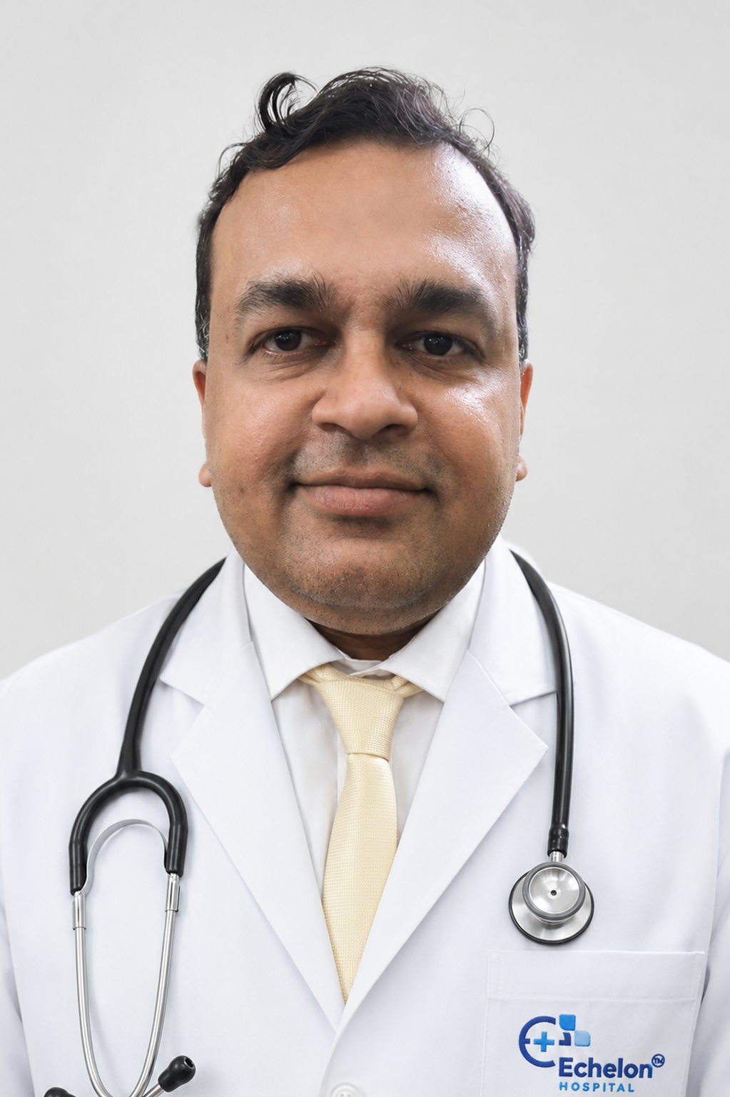 Male doctor in a white coat with a stethoscope around his neck and a pale yellow tie.