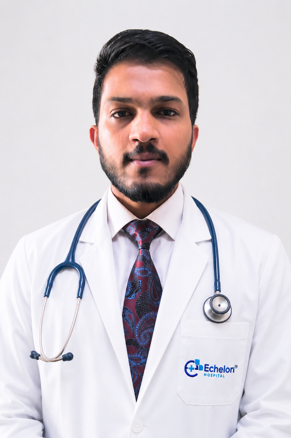 Portrait of a male doctor in a white coat with a stethoscope, facing the camera; pocket displays the Echelon Hospital logo.