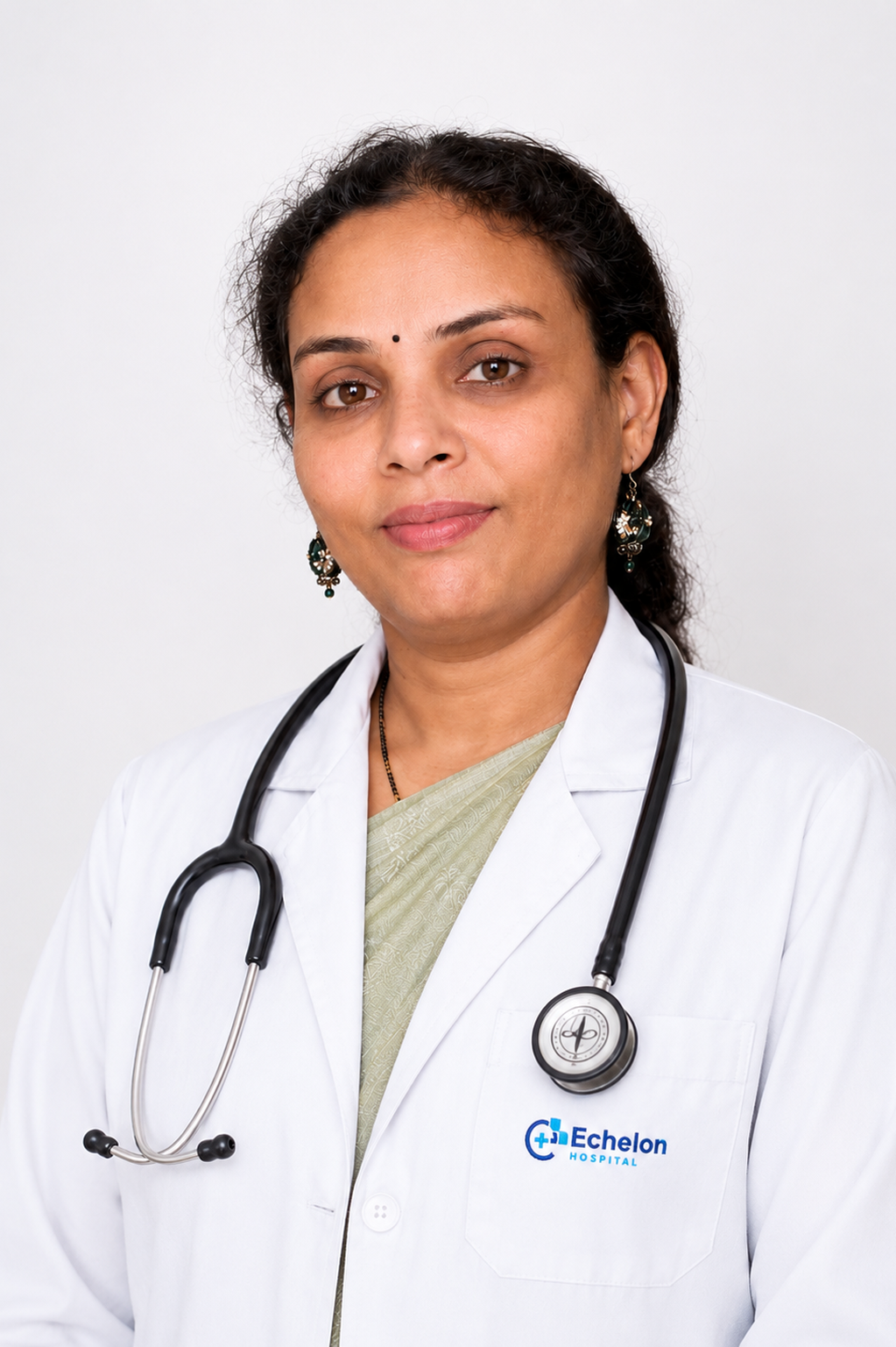 Portrait of a female doctor in a white coat with a stethoscope around her neck, Echelon Hospital logo on the pocket, looking at the camera.
