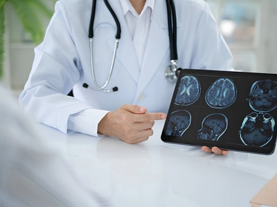 Doctor in a white coat with a stethoscope shows brain MRI scans on a tablet.